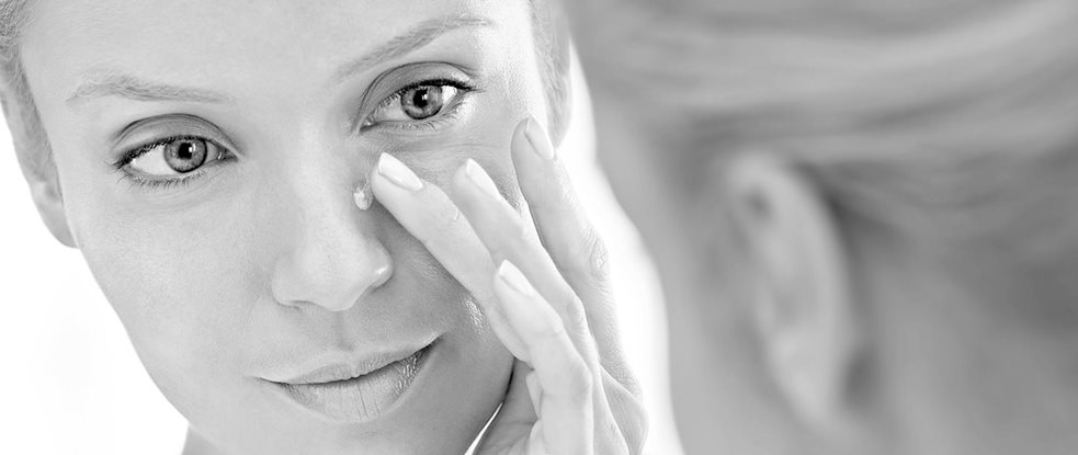 Mujer aplicándose crema en su nariz